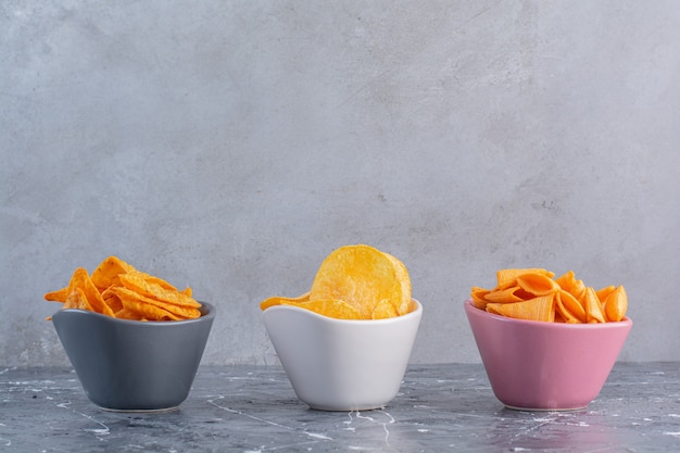 Free photo assortment potato chips in bowls, on the marble surface