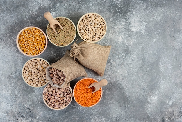 Assortment of raw dry legumes composition on marble table surface.