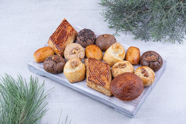 Assortment of tasty cookies on wooden board.