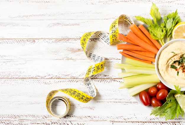 Free Photo assortment of vegetables on plate with hummus and measuring tape