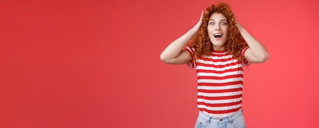 Free Photo astonished surprised emotive happy redhead girl receive incredible offer gift grab curly hair open m