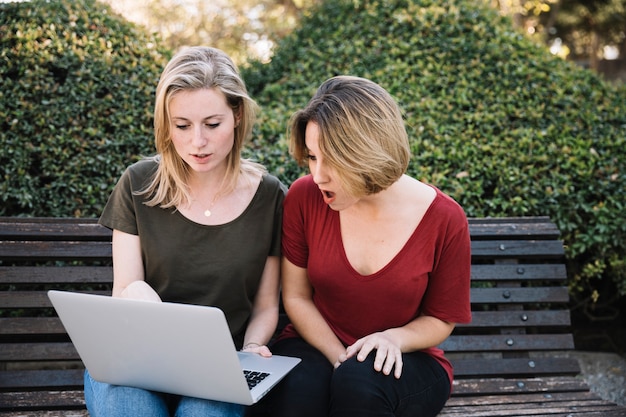 Astonished women using laptop in park