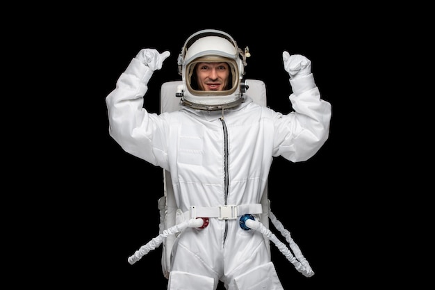 Free photo astronaut day spaceman in galaxy excited landed space suit glass helmet fists up happy