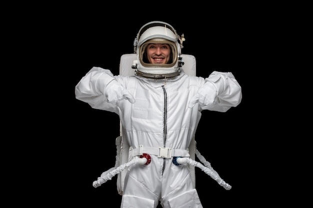 Free photo astronaut day spaceman in outer space cosmos space suit helmet smiling pointing down