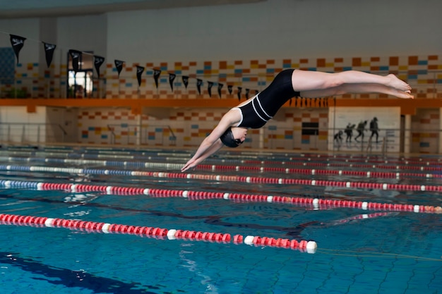 Athlete jumping in pool full shot