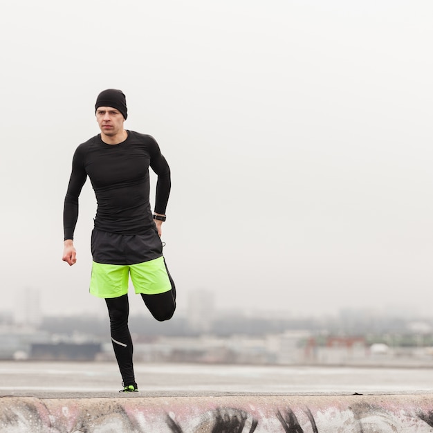 Free photo athlete stretching leg on a grey day