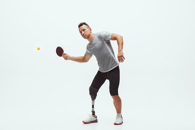 Athlete with disabilities or amputee isolated on white. Professional male tennis player with leg prosthesis training