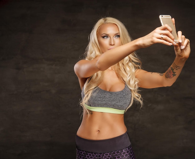 Free Photo athletic blond female taking selfie by smartphone.