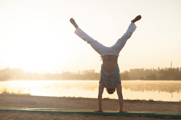 Athletic capoeira performer workout training on the beach sunrise