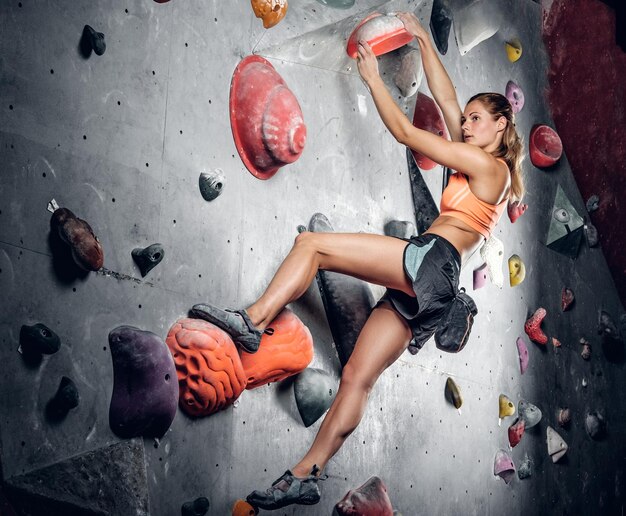 Athletic female climbing on a climbing wall with light effect on the image.