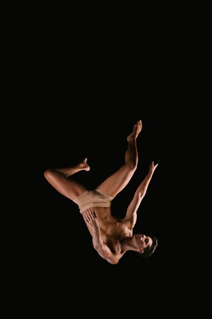 Athletic male exercising on black background