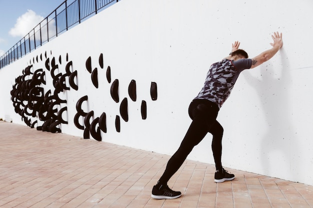 Free photo athletic man doing push-ups on wall