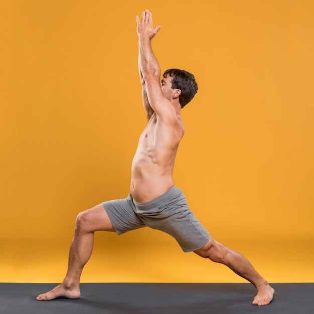 Free photo athletic man doing yoga pose on mat