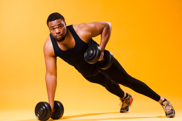 Athletic man holding weights while exercising