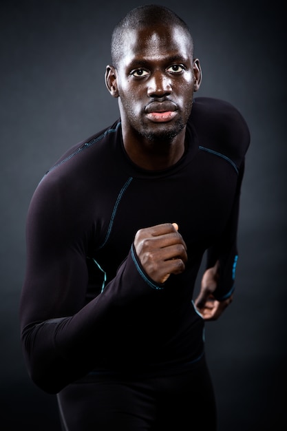 Athletic man running in black background.