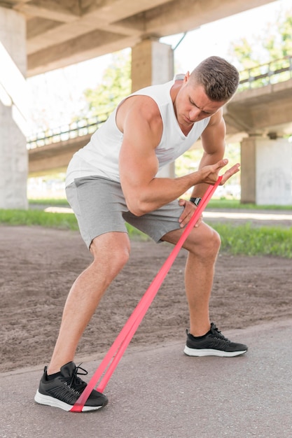 Athletic man working out with a red stretching band