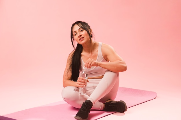 Athletic woman in gym outfit resting on mat