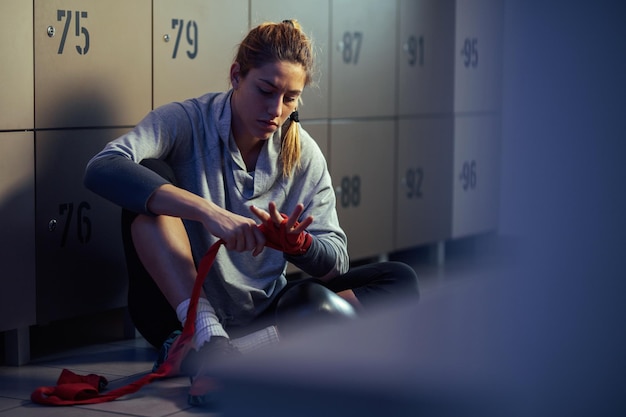 Free Photo athletic woman preparing for exercising and wrapping her hand with a strap