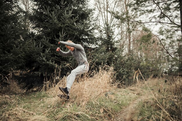 Athletic young male leaping over the grass while sport training