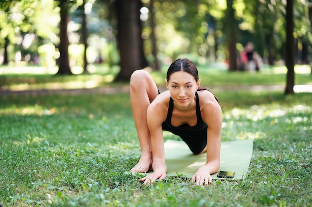 Athletic young woman doing yoga in the Park in the morning, women's training on a yoga Mat