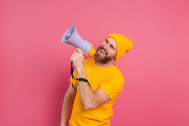 Attention! European man shouting in megaphone on pink background