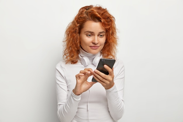 Free photo attentive woman focused at smartphone device, makes song playlist