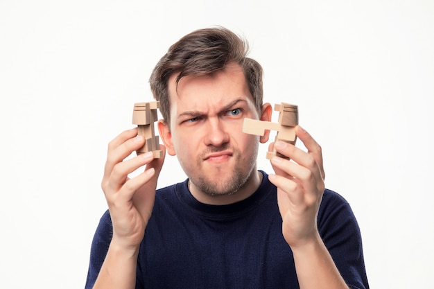 Attractive 25 year old business man looking confused with wooden puzzle.