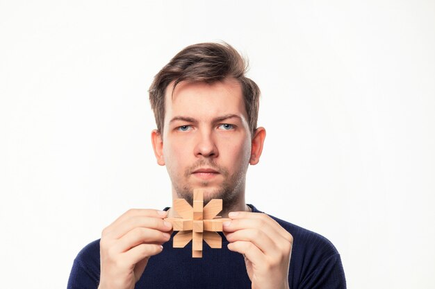 Attractive 25 year old business man looking confused with wooden puzzle.