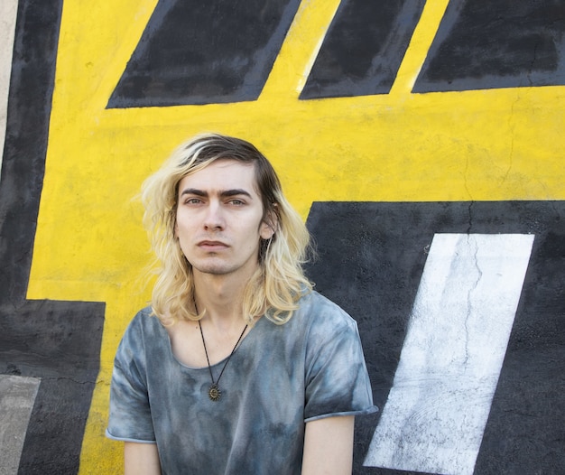 Free photo attractive armenian guy with a hat looking at the front on a yellow and black wall