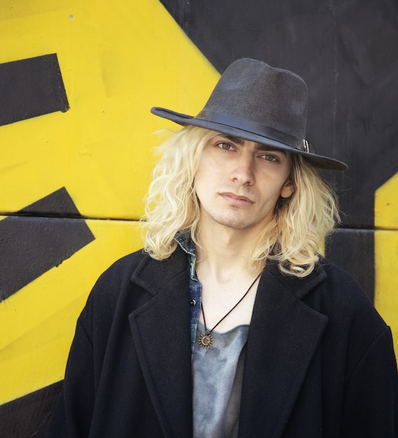 Free photo attractive armenian guy with a hat on a yellow and black wall