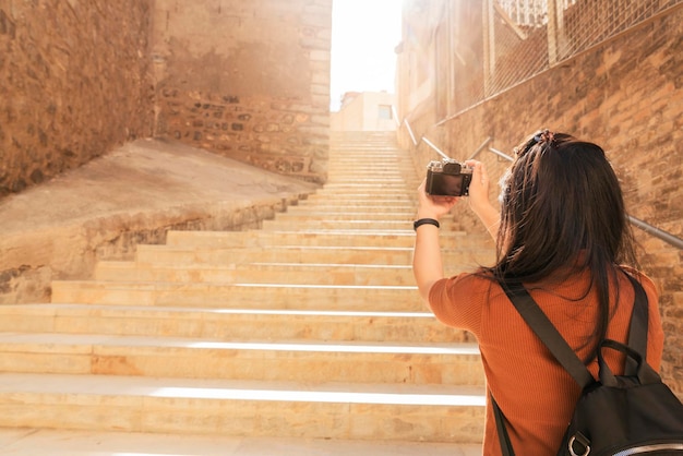 Free photo attractive asian female traveller tourism hand use camera sightseeing old stone stair hallway in cartagena spain with happiness and cheerful travel journey concept