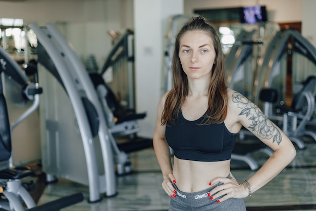 Attractive athletic girl stands on the background of simulators in the gym. healthy lifestyle.