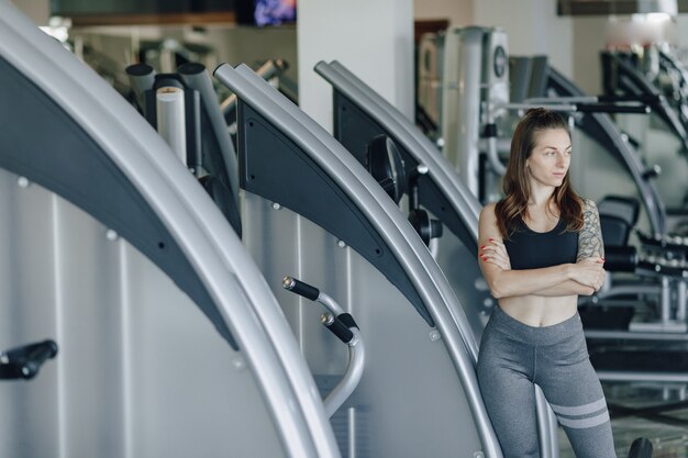 Attractive athletic girl stands on the wall of simulators in the gym. healthy lifestyle.