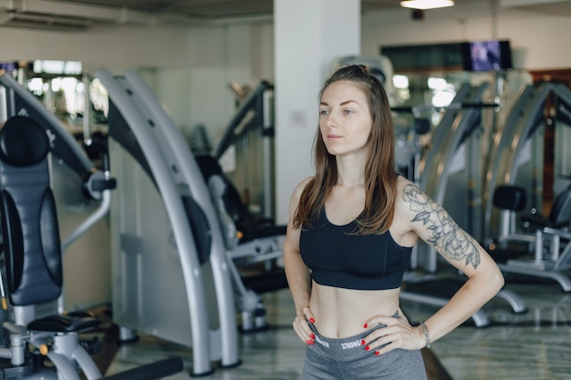 Attractive athletic girl stands on the wall of simulators in the gym. healthy lifestyle.