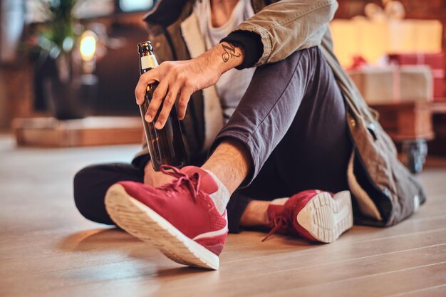 Attractive bearded Indian male drinks craft beer in a room with Christmas decoration.