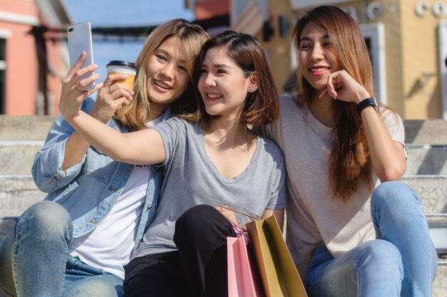 Attractive beautiful asian woman using a smartphone while shopping in the city