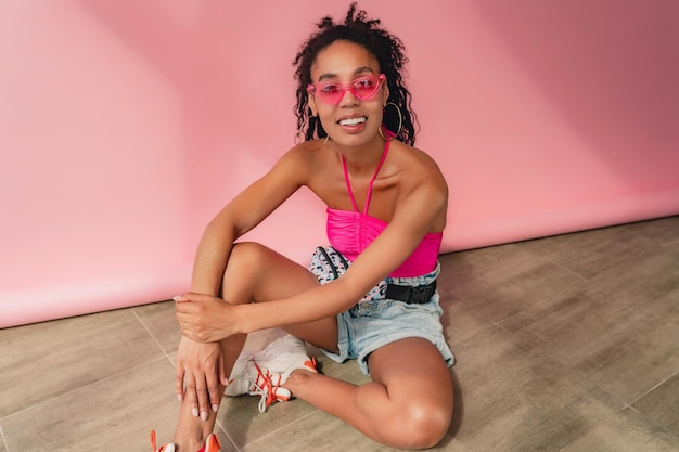 Attractive black african american woman in stylish outfit on pink background