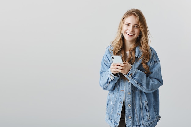 Attractive blond girl with mobile phone smiling