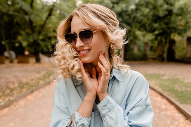 Attractive blond smiling candid woman walking in park in summer outfit