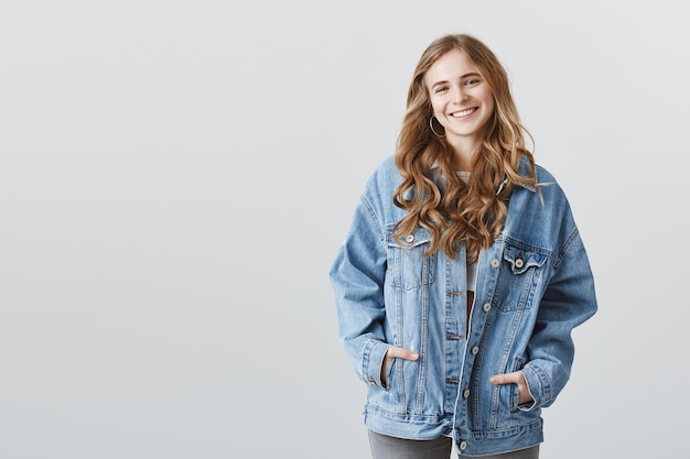 Free Photo attractive blonde college girl in denim jacket smiling happy