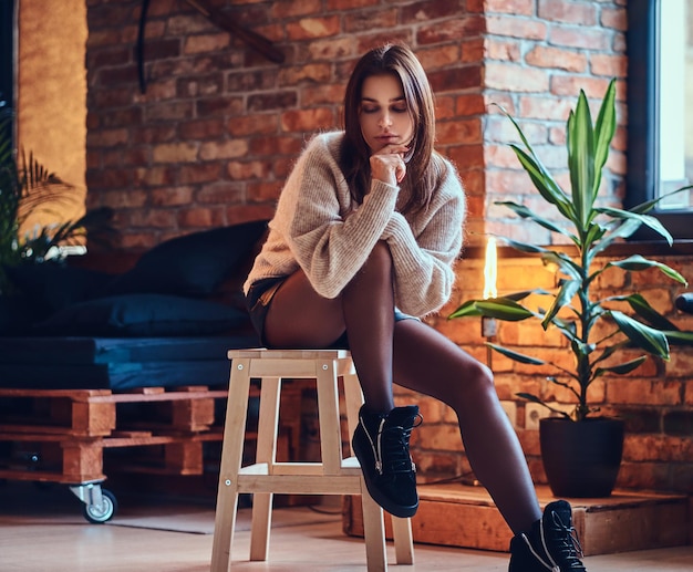 Attractive brunette female posing near the window in a room with loft interior.