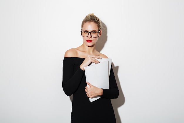 Attractive business woman in dress and eyeglasses holding documents