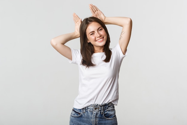 Attractive carefree girl showing bunny ears on head and smiling cute.