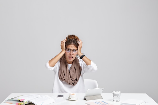 Free photo attractive casually dressed young female secretary in stylish eyewear holding hands on head