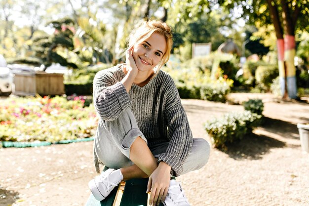 Attractive charming girl with green eyes sits in cozy place in comfortable position and looks into lens Fulllength photo of model in soft sweater