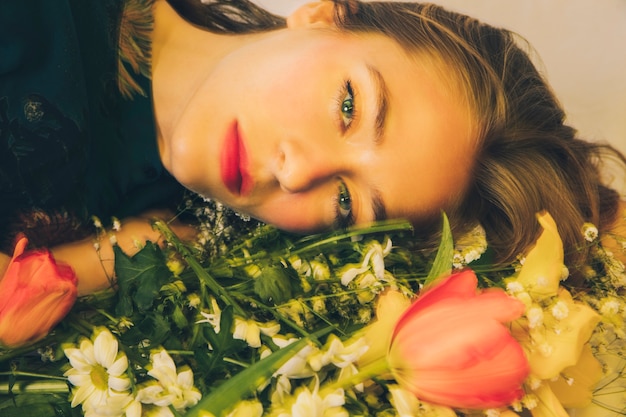 Attractive charming woman lying with bouquet of flowers