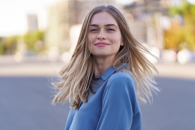 Free photo attractive cheerful blonde girl with flying long hair smiling laughing in the city