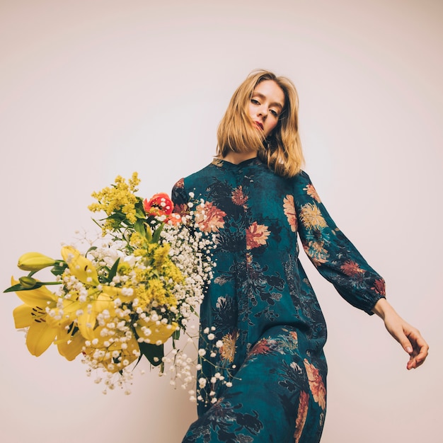 Attractive confident woman in dress with bouquet of fresh flowers