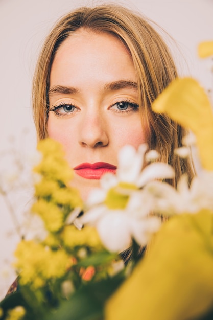 Attractive confident woman standing behind blooms