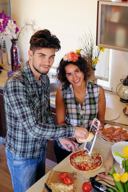 Attractive couple of brunette female and a male in fleece shirt cooking the food in a home family kitchen.